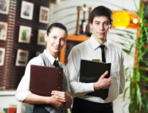 Waitress girl and waiter man of commercial restaurant in uniform waiting an order with menu